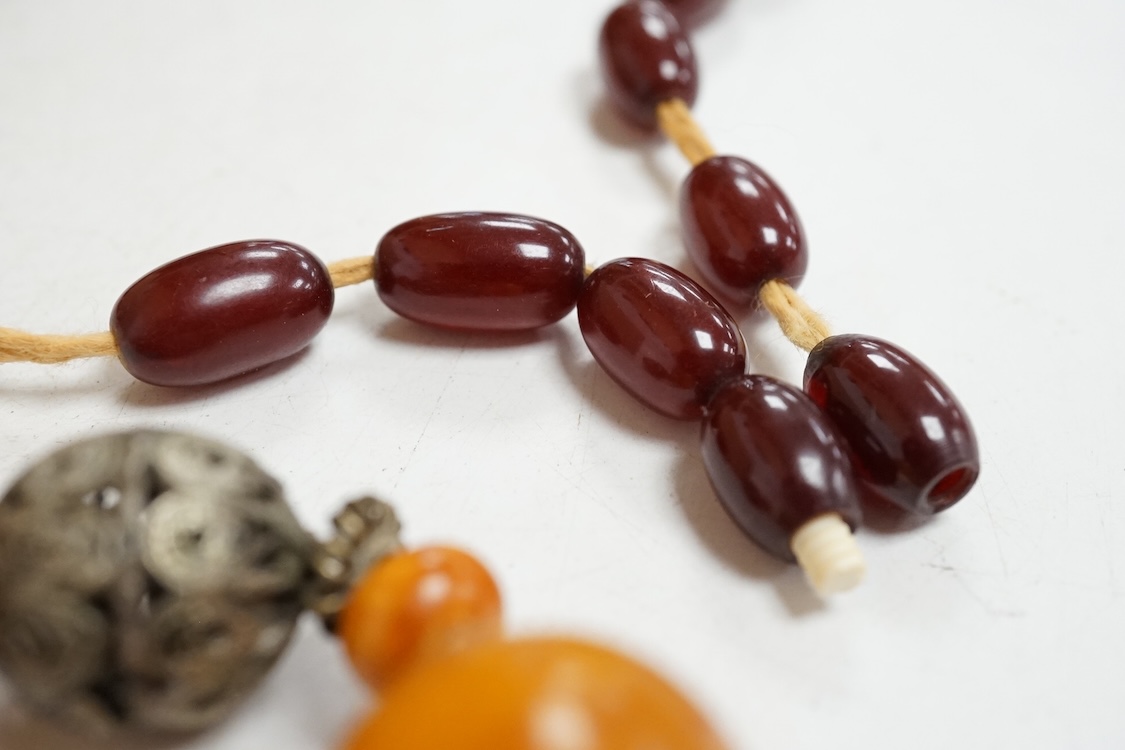 A single strand amber bead necklace, with filigree metal spacers, 48cm, gross 84 grams, together with a group of loose graduated simulated cherry amber beads, gross weight 117 grams.